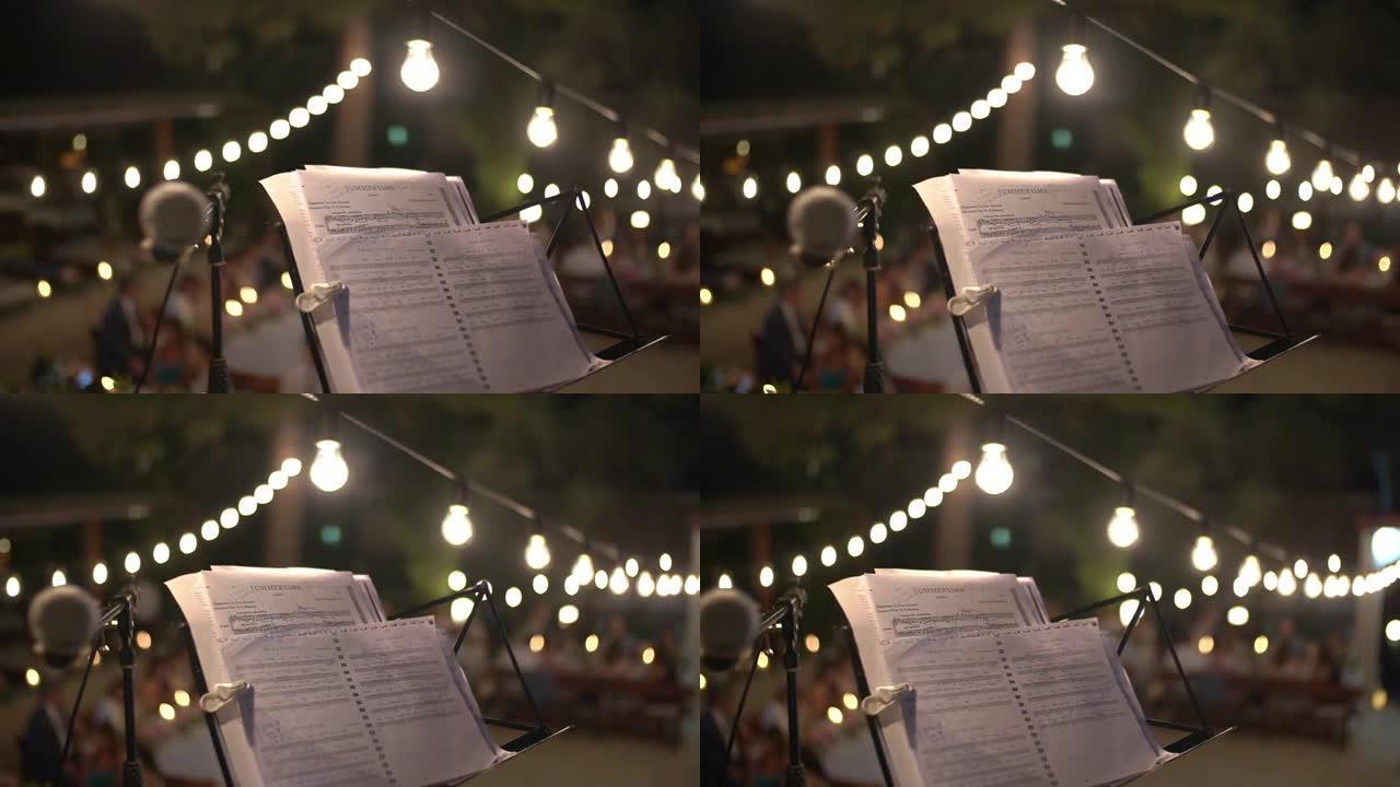 音乐台上的笔记，节日平台中间的麦克风旁边，装饰着灯泡的花环