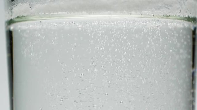 慢动作特写在一杯水，苏打饮料中的白色小气泡