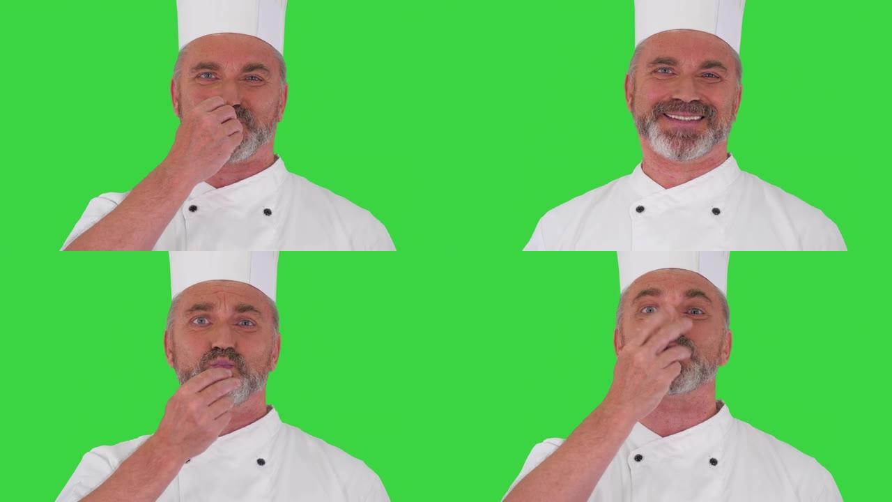 年长的专业厨师在绿色屏幕上向相机展示美味的手势，色度键