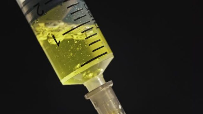 在大流行期间，将黄色药物冠状病毒疫苗拨入黑色背景上的注射器中。冠状病毒疫苗接种概念，新型冠状病毒肺炎
