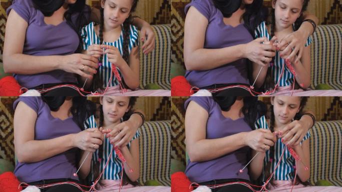 30多岁的迷人黑发妈妈和八岁的女儿坐在沙发上的房间里学习编织，并在笔记本电脑屏幕上观看互联网上的视频