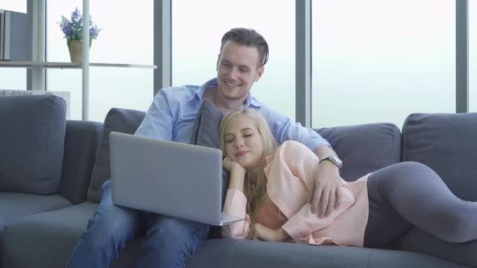 微笑的商务金发女郎，白人夫妇在沙发上放松和看电影，在检疫一起度过电晕病毒概念。