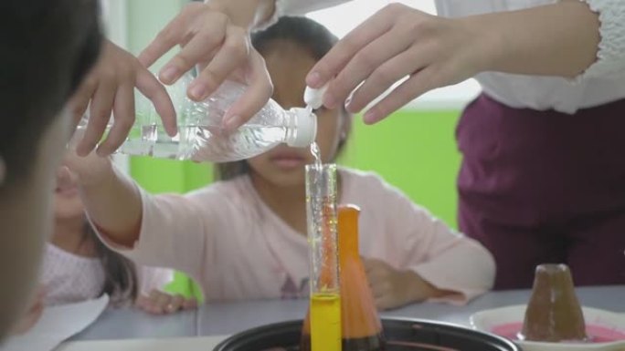 拍摄小组儿童和他们的女教师观察一个科学实验与颜色在一个罐子，教育，科学，技术，儿童和人的概念