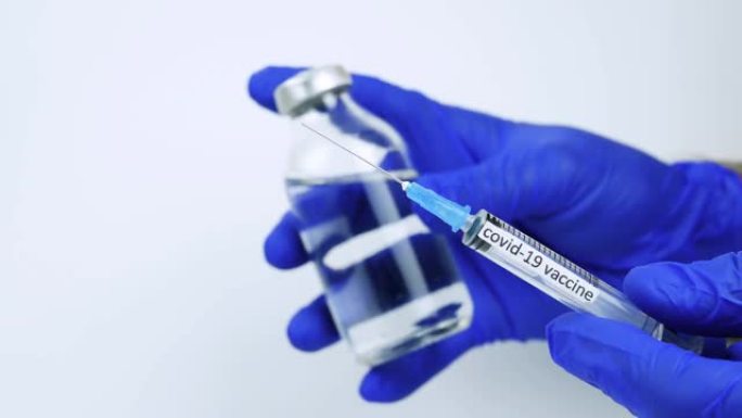 演示针对冠状病毒感染的疫苗，带有铭文疫苗的注射器，医生，医务人员手中的一罐药物。