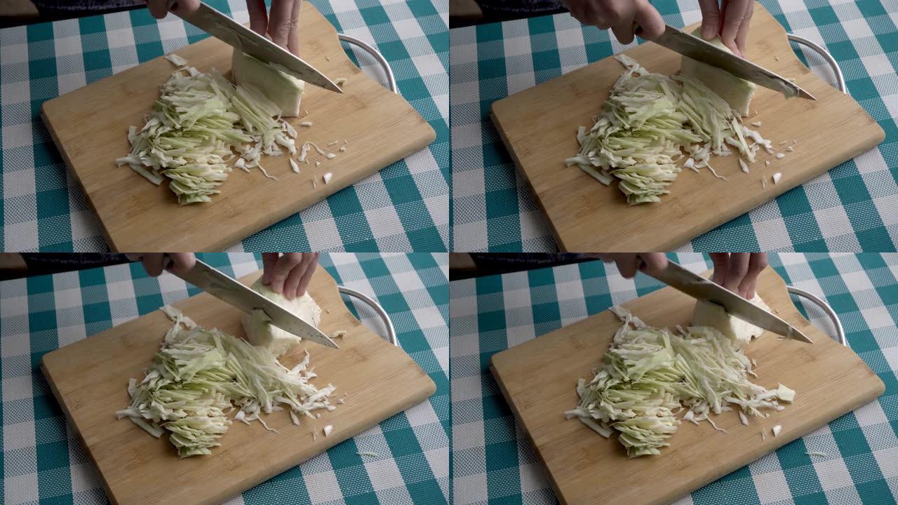 女人用大刀在厨房的木板上切白菜的手的特写。健康饮食的概念。不露面。从顶部看。4K。