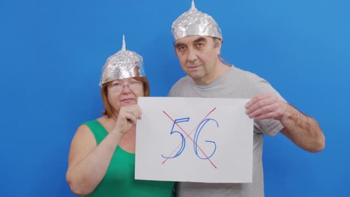 男人和女人拿着没有5g标志的标语牌。站在蓝色背景下抗议5g技术和5g兼容天线部署。
