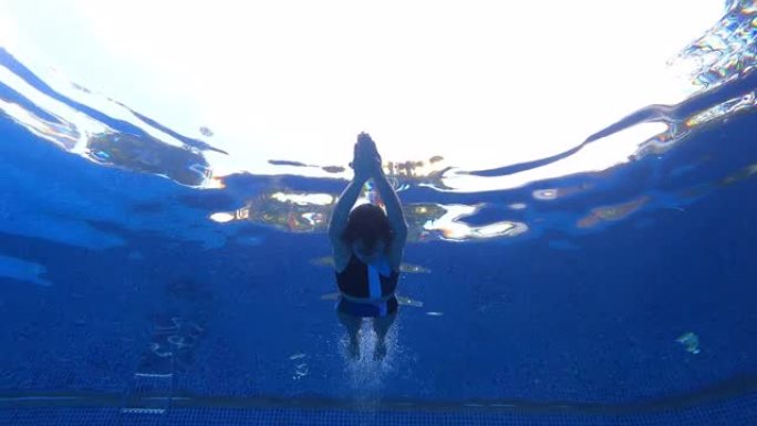 水下仰视女人穿两件套泳衣在海豚踢流线游泳