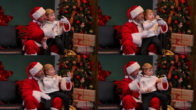 一个孩子坐在膝盖上的圣诞老人通过智能手机上的视频通话进行交流。特写。慢动作