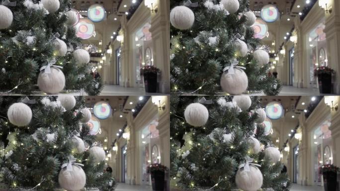 在商店橱窗的背景下，一棵装饰有毛线球的圣诞树站在购物中心的大厅里