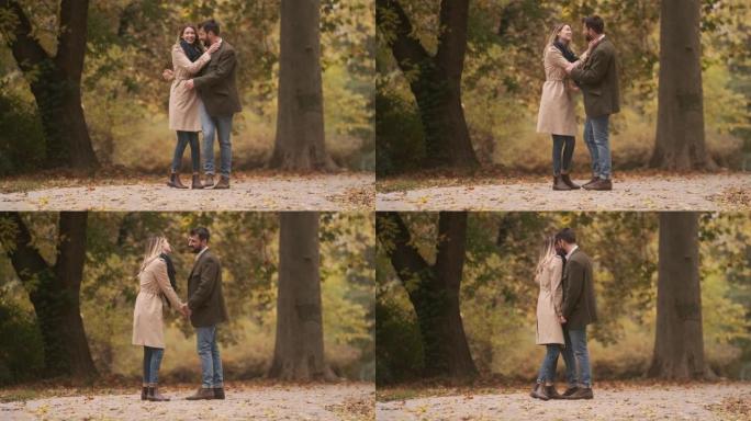 英俊的年轻夫妇在秋天的公园里散步