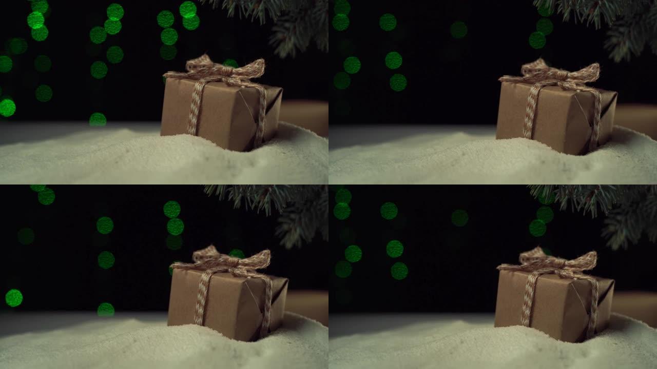 在树下的雪地里躺着一个盒子，里面有一个蝴蝶结，手纸。圣诞灯
