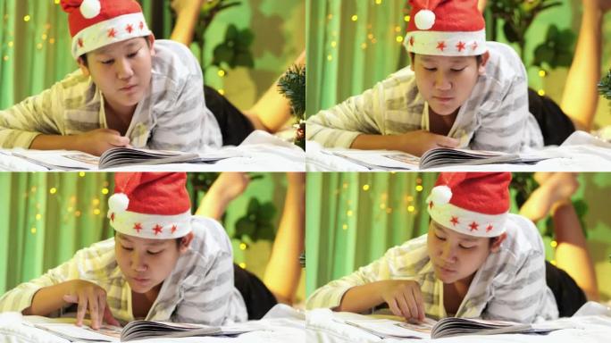 快乐的亚洲男孩戴着圣诞老人的帽子，看书，晚上躺在床上，穿着圣诞装饰品，生活方式的概念。