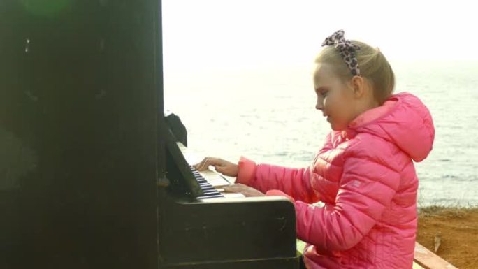 有趣的小女孩在海岸上弹奏一架旧钢琴