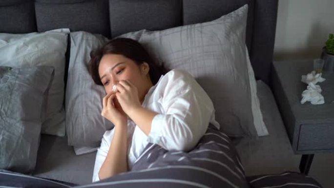 年轻亚裔妇女病患在床上咳嗽打喷嚏