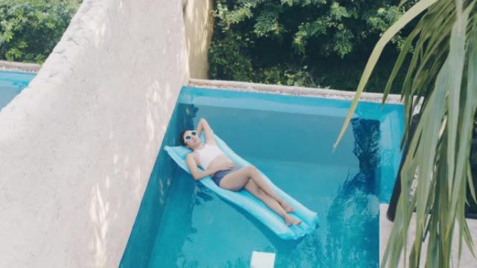 周末假期，亚洲幸福女人在海边度假酒店的游泳池里放松。快乐旅行的概念。4k慢动作。