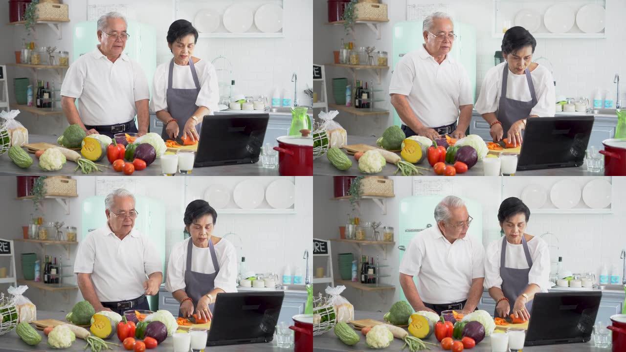 亚洲老年夫妇在家里厨房做饭时使用笔记本电脑。70年代老年男女关系退休生活方式观念