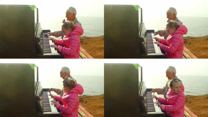 老人和小女孩在海边散步时一起弹旧钢琴