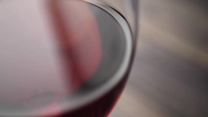 豪华红酒。美味的葡萄酒，由美味的红葡萄在棕色背景的桌子上的酒杯中制成。摄像机向右移动。慢动作。特写