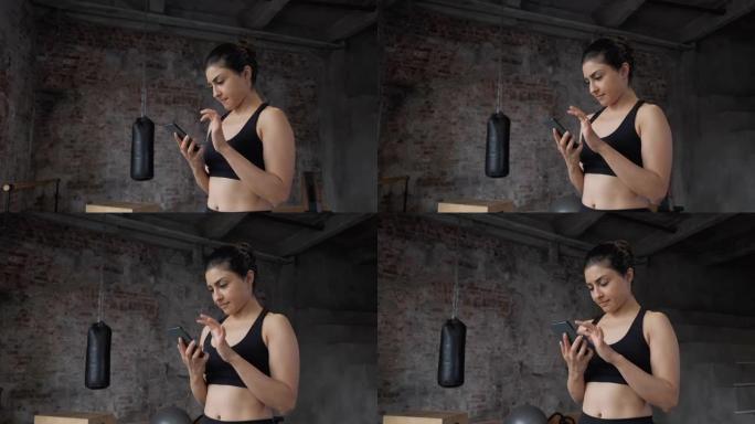 年轻快乐的印度健身女子在健身房用手机展示
