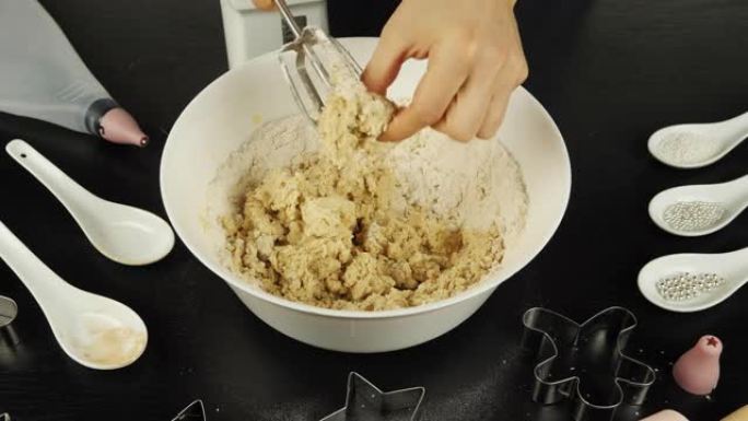 女性的手从搅拌机刀片上取下生面团，制成加香料的姜饼饼干或饼干。自制糕点或面包店的制备过程