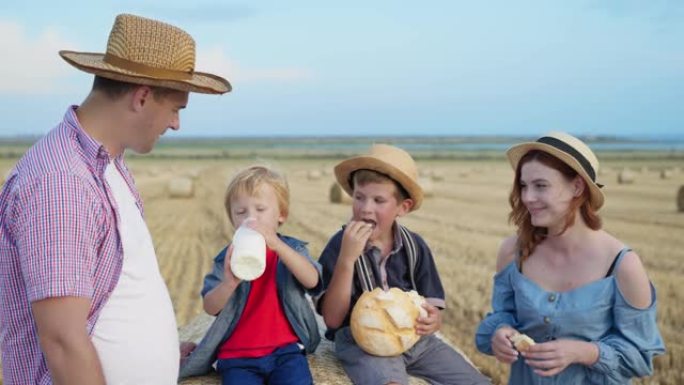 野餐中的家人，有爱心的父亲和他慈爱的妻子和儿子一起吃面包，洗牛奶，同时在麦田里用干草在天空上放松