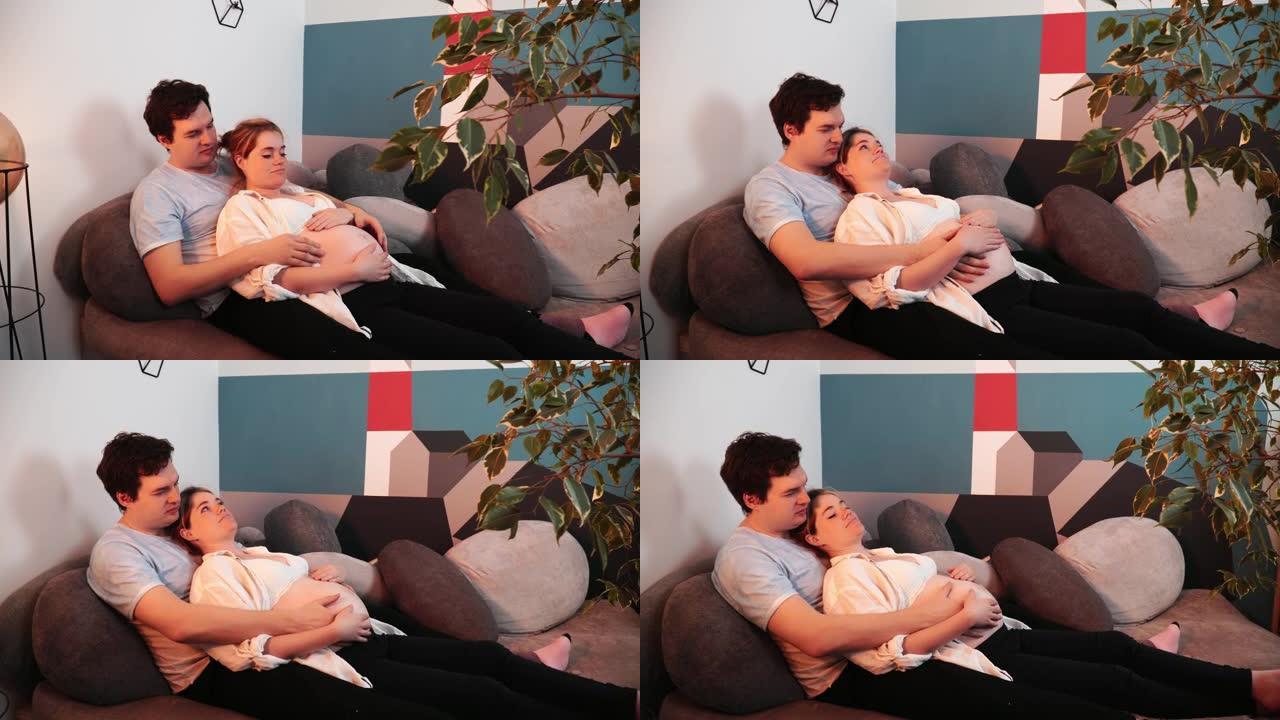 一名孕妇躺在他丈夫的胸前，他抚摸着她的肚子