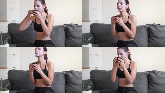 年轻的千禧一代妇女在家在脸上涂布面膜并使用电话。健康放松时间