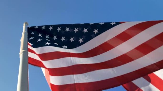 美国国旗在旗杆上飘扬，背面是岩石山