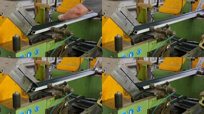 工人用手在工厂的机器上用圆锯切割铝型材。