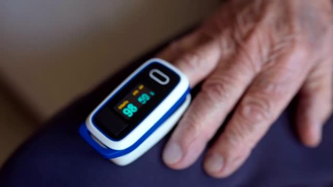 老人在家中用数字脉搏血氧仪测量血液中的血氧饱和度，男性患者肺炎用手指佩戴血氧仪监测血氧率。预防性医疗