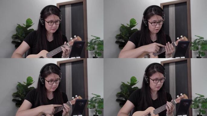 亚洲女性在家自学网络学习演奏夏威夷四弦琴。