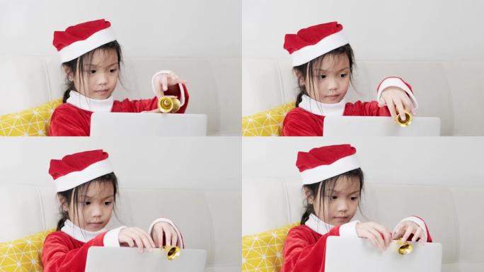 快乐的亚洲女孩穿着圣诞老人服装，在家坐在沙发上，生活理念。