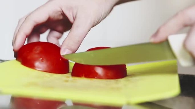 用不锈钢刀在绿色板上手工切割成熟的红番茄