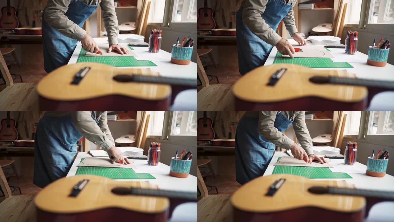 一个无法识别的人在纸上切割吉他的形状，在车间里制作新模型