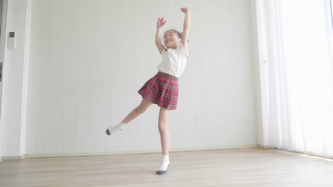 一个穿白色t恤和迷你裙的小女孩有能量。她喜欢在房间里跳舞和跳跃。