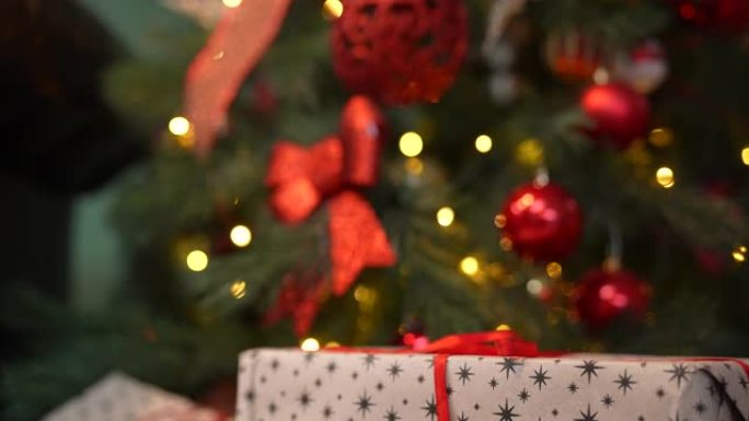 漂亮的礼品盒位于圣诞树附近，上面装饰着发光的花环和球。带礼品盒的新年背景。庆祝圣诞节。节日气氛。特写