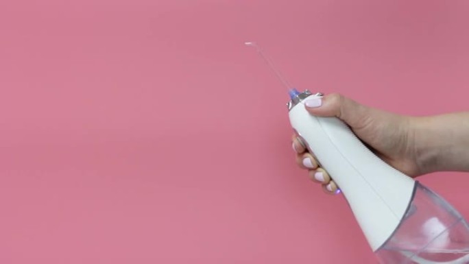 女性手握牙科冲洗器在粉红色背景，复制空间