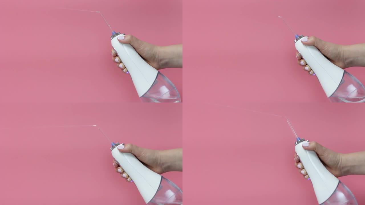 女性手握牙科冲洗器在粉红色背景，复制空间