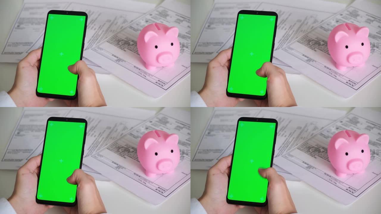 电话与绿屏和存钱罐付款收据，税务文件在白色背景顶视图。智能手机chromakey向不同方向滑动。复制
