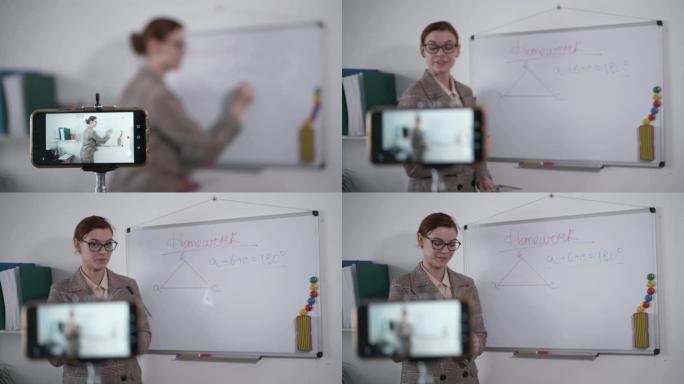 在线课程，戴着视觉眼镜的女教师用手机为她的学龄前儿童在检疫、距离期间进行现场直播白色磁板背景