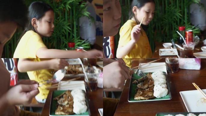 快乐的亚洲儿童在午餐时间一起在餐厅吃日本食物，生活方式理念。烤沙巴鱼配酱汁和饭团。