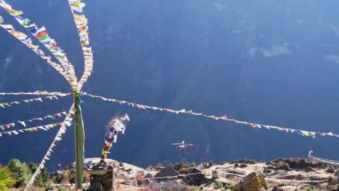 五颜六色的佛教祈祷旗在强风和着陆直升机上飘扬，在尼泊尔夏尔巴人村庄南切巴扎尔上空造成灰尘。