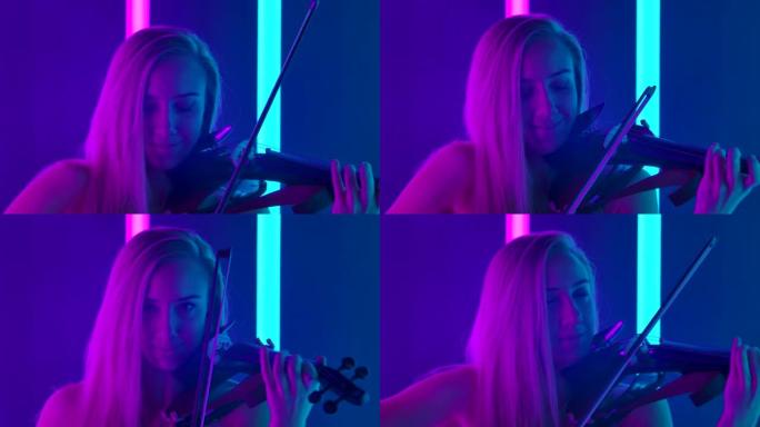 微笑的女音乐家在工作室里熟练地拉小提琴。金发女郎在明亮的霓虹灯中展示了她的技巧。特写。慢动作