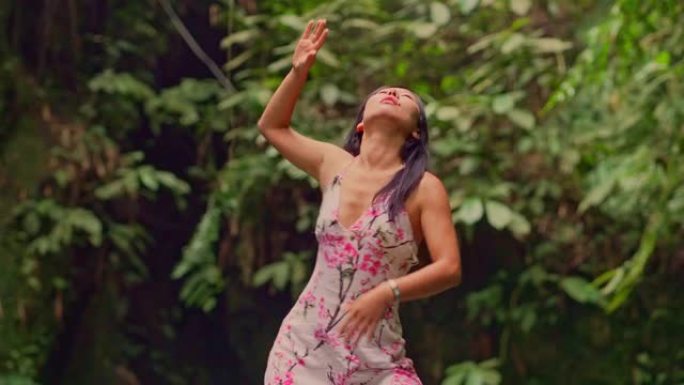 丛林中的亚洲传统舞蹈 -- 年轻美丽性感的中国女性穿着时尚的服装在绿色雨林背景下以和谐热情的感觉跳舞