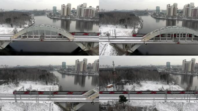 跟踪在冬天的城市背景下，在河上的一座桥上拍摄了高速旅客列车的运动。乘火车旅行。