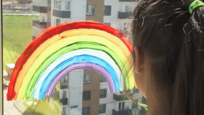 女孩在家里检疫时在窗户上画彩虹。