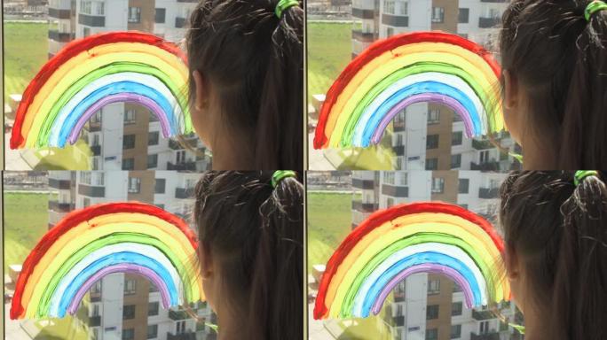 女孩在家里检疫时在窗户上画彩虹。