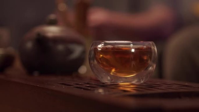 热情好客的主人用玻璃碗招待客人美味的日本茶。没有脸的特写