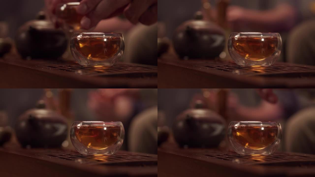热情好客的主人用玻璃碗招待客人美味的日本茶。没有脸的特写