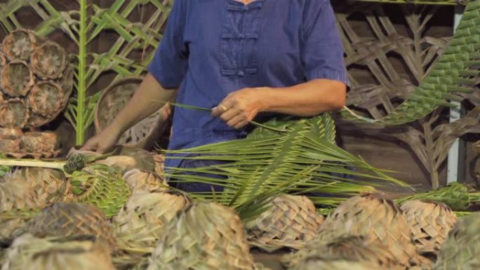亚洲老妇用天然棕榈树产品的叶子制作泰国当地编织草帽或帽子，泰国。在市场上编织。古老的传统生活方式。